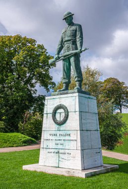 Kopenhag, Danimarka - 13 Eylül 2010: Vore Faldne yeşil bronz heykeli, Kastellet 'in önündeki kireç taşı heykeli, kale, gri gökyüzü altında yeşil yapraklar