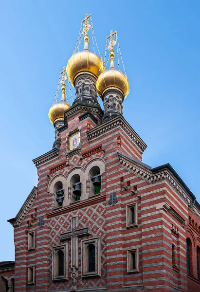 stock image Copenhagen, Denmark - September 13, 2010: St. Alexander Nevsky Russian Orthodox church red and white facade with tripple golden domes on top against blue sky. Bells and painting