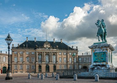Kopenhag, Danimarka - 13 Eylül 2010: Amalienborg Meydanı. Frederik V yeşil bronz binicilik heykeli mavi bulutların altında mermer kaidede. Frederik Sarayı arkada.