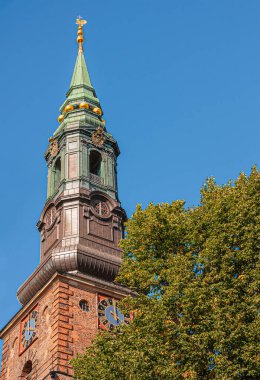Kopenhag, Danimarka - 13 Eylül 2010: Sankt Petri Kirke, kilise, mavi gökyüzüne karşı. Altın süsler ve saat, köşede yeşil yapraklar.