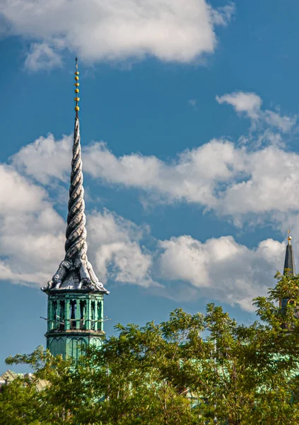 丹麦哥本哈根 2010年9月13日 龙塔关闭 其螺旋形尾翼在绿色树叶后面的证券交易所大楼顶部 在蓝色的云彩下 — 图库照片