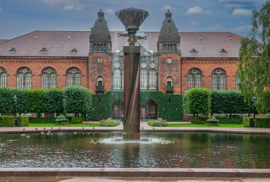 Kopenhag, Danimarka - 14 Eylül 2010: Kraliyet Kütüphanesi yeşil bahçe, havuz kenarındaki sütun üzerindeki kırmızı tuğladan Yahudi müzesinin önündeki mavi bulutların altındaki çeşme.