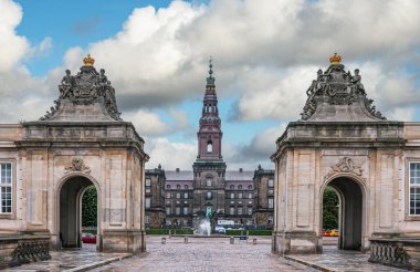 Kopenhag, Danimarka - 14 Eylül 2010: Mavi bulutlar altında Christiansborg Slot 'un bej grisi, yontulmuş, anıtsal avlu girişinin kapatılması. Çeşme ve heykel ortada