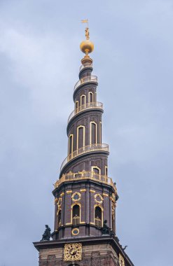Kopenhag, Danimarka - 14 Eylül 2010 Vor Frelsers Kilisesi. Saat kulesi açık mavi gökyüzüne karşı izole. Spiral ve saatin altın süslemesi. Corniche 'deki heykeller ve en üstteki altın küre