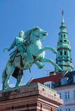 Kopenhag, Danimarka - 15 Eylül 2010: Absalon 'un Binicilik heykeli mavi gökyüzünün altındaki Hojbro Plads' ta duruyor. Nikolaj Kunsthallen eski kilise kulesi arkada.