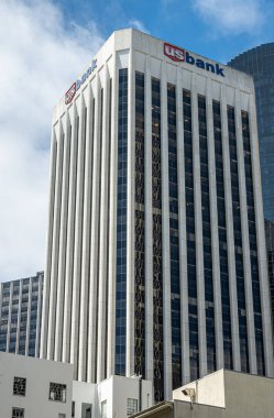 San Francisco, CA, ABD - 12 Temmuz 2023: Kaliforniya ve Drumm caddelerinin köşesindeki USBank ofis kulesinin kule bölümü mavi bulutların altında. Dikey çizgiler ve koyu mavi cam.