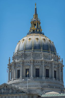 San Francisco, CA, ABD - 12 Temmuz 2023: bej taşlı belediye binası girişte doğu cephesi ve mavi gökyüzü altında dev kubbe. Altın madalyalar kulede ve kulede. Üzerinde 3 Bayrak: Ülke, eyalet, şehir