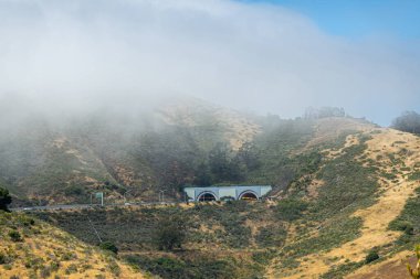 San Francisco, CA, ABD - 12 Temmuz 2023: Marin ilçesindeki Golden Gate köprüsünün karşısındaki Robin Williams tüneline güney girişi ve çıkışı olan manzara manzarası. Sis ve yeşil tepeler