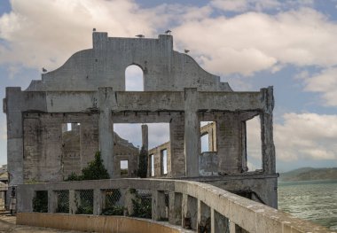 San Francisco, CA, ABD - 12 Temmuz 2023: Alcatraz Adası, doğu kıyısı, çatısız harabe, mavi bulutlar altında yakın çekim. Yeşil körfez suyu