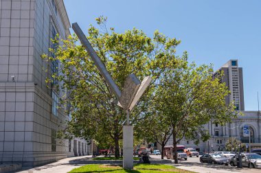 San Francisco, CA, ABD - 12 Temmuz 2023: Fulton ve Larkin caddelerinin köşesindeki Halk Kütüphanesi 'nin köşesindeki Double L Excentric Gyratory heykeli. Arabalar ve yeşil yapraklar