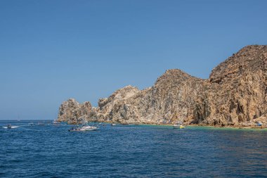 Meksika, Cabo San Lucas - 16 Temmuz 2023: Bej-kahverengi kayalık tepeler okyanusa doğru uzanıyor.