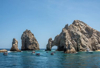 Meksika, Cabo San Lucas, 16 Temmuz 2023, El Arco kayalık yarımadasının doğu ucunda, mavi gökyüzünün altında. Birkaç küçük turist teknesi yeşil suların üzerinde.