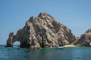 Meksika, Cabo San Lucas - 16 Temmuz 2023: güneyden, körfez tarafından, El Arco 'dan ve Playa de los Amantes sahilinin bir kısmından gri-kahverengi kayalıklar arasında görüldü. Ön tarafta küçük turistler var.