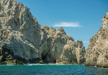 Meksika, Cabo San Lucas - 16 Temmuz 2023: yeşil okyanus suyundaki uzun gri kayalar arasındaki Reserva de Los Marina kanalının güney manzarası. 