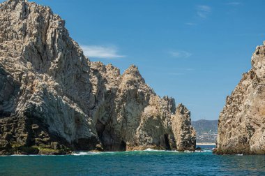 Meksika, Cabo San Lucas - 16 Temmuz 2023: Reserva de Los Marina 'nın güney manzarası, yeşil okyanus suyundaki uzun gri kayalar arasında açık kanal. Şehir manzarası ve ufukta plaj