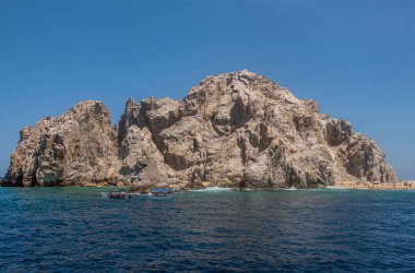 Meksika, Cabo San Lucas - 16 Temmuz 2023: Reserva de Lobos Marinos kayalık uçurumları okyanus ile Playa de los Amantes arasında, sevgililer plajı mavi gökyüzü altında. Önde küçük gezi tekneleri var.