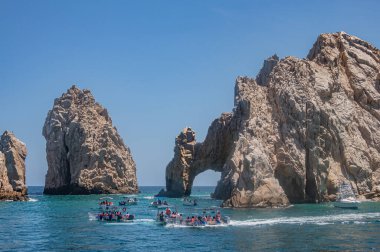 Meksika, Cabo San Lucas - 16 Temmuz 2023: Reserva de Lobos Marinos kayalığı ve El Arco kayalık kemeri. Körfezden okyanusa bir sürü küçük gezici tekneyle.