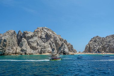 Meksika, Cabo San Lucas - 16 Temmuz 2023 Playa de los Amantes, Lobos Marinos Reserva 'nın sahil kenarı, mavi gökyüzü altında. Bir sürü banyo ve küçük gezi tekneleri var.