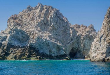 Meksika, Cabo San Lucas - 16 Temmuz 2023 Rezerv de Lobos Marinos 'ta yeşil okyanus suyuna inen gri bej kayalık kayalıklarda yakın plan mağara