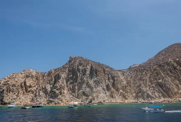 Meksika, Cabo San Lucas - 16 Temmuz 2023 Playa el Balconcito, SE körfezinin arkasındaki küçük sahil gri-bej kayalık kayalıkların altında. Yeşil sularda küçük eğlence tekneleri. Mavi gökyüzü