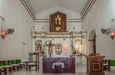 San Jose del Cabo Centro, Meksika - 16 Temmuz 2023 Sunak, çiçekler ve heykeller ile misyon kilise chancel. Ders masası ve sandalyeler
