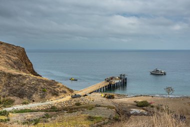 Santa Cruz Adası, CA, ABD - 14 Eylül 2023: feribot, kamyon ve küçük yelkenli işçileri olan Scorpion Anchorage iskelesi. Mavi bulutlar, dağların yamaçlarında kahverengi otlar.