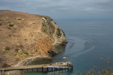 Santa Cruz Adası, CA, ABD - 14 Eylül 2023: Akrep Anchorage iskelesi kaçakçılar yolu boyunca yukarıdan görüldü. Okyanusun üzerindeki sisli gökyüzü ve uçurumlarla kaplı kahverengi ot tepesi