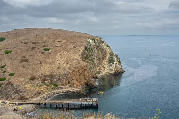 Santa Cruz Adası, CA, ABD - 14 Eylül 2023: Akrep Anchorage iskelesi kaçakçılar yolu boyunca yukarıdan görüldü. Mavimsi okyanusun üzerindeki bulutlar ve uçurumlarla kaplı kahverengi tepeler. Yat görünürde