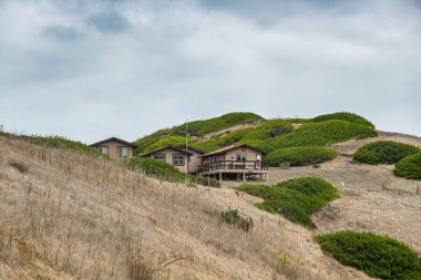 Santa Cruz Adası, CA, ABD - 14 Eylül 2023: ABD Ulusal Parkı Hizmet bungalovu Akrep Çiftliği 'nin üzerindeki Cavern Crest yakınlarında mavi bulutların altında. Büyük yeşil çalılar