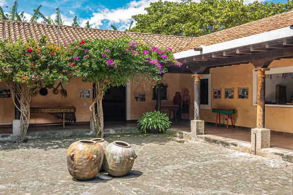 グアテマラ ラアンティグア 2023年7月20日 フィンカ シュティア美術館 中庭は1階建ての展示棟に囲まれています 青い雲の下の花と緑の葉 ストックフォト