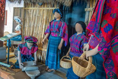 Guatemala, La Antigua - 20 Temmuz 2023 Finca La Azotea müzeleri. Dişi bebekler elle çatırdayan tahılları taş kapta havan topu kullanarak öğütüşlerini izliyor. Bambu arkaplanı