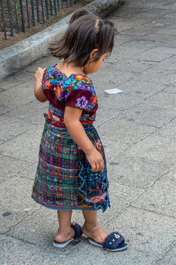 Guatemala, La Antigua - 20 Temmuz 2023: Kapanış, Plaza Belediye Başkanı 'nın gri asfalt yüzeyi üzerinde duran geleneksel giysili küçük kız,, 