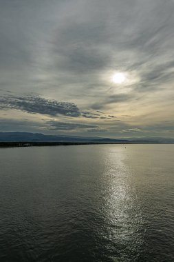 Kosta Rika Puntarenas - 22 Temmuz 2023: Portre, kasabanın doğusundaki Nicooya Körfezi sahili sabah güneşinin altında gri ve mavi bulutları delip geçiyor. Merkez Dağ Sırası