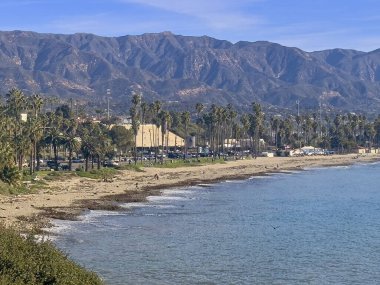 Santa Barbara, CA, ABD - 28 Ocak 2024: City College La Playa Stadyumu seyirci standlı. Pasifik Okyanusu plajı, palmiye ağaçları ve mavi bulutların altında dağ sıraları.