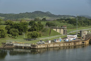 Panama Kanalı, Panama - 24 Temmuz 2023: Miraflores kuzey bölümündeki rıhtımlarla kıyı şeridini kilitliyor. Mavi gökyüzünün altındaki yeşil manzara