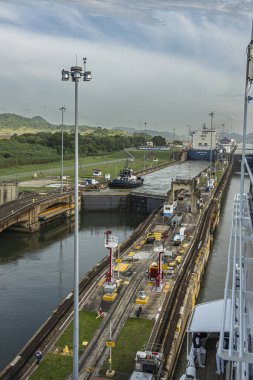Panama Kanalı, Panama - 24 Temmuz 2023: Portre, Miraflores bir römorkör ve CMA CGM Neva konteynır gemisi ile kuzeye giden 2 odanın kapılarını kilitledi. Yeşil manzara