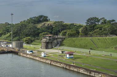 Panama Kanalı, Panama - 24 Temmuz 2023: Miraflores mavi bulutlar altında kuzeye giden yeşil kıyı şeridini, gözetleme kulesini ve diğer binaları kilitledi. Arkadaki yeşil orman.