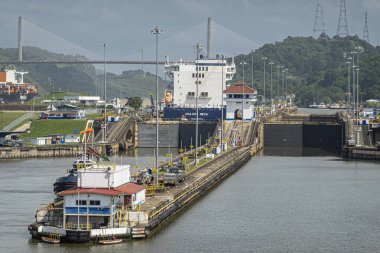 Panama Kanalı, Panama - 24 Temmuz 2023 Güney Cephesi, Pedro Miguel Centennial Köprüsü ile gri bulutların altında, Pan-Amerikan karayolu köprüsü. Yeşil tepeler. Konteyner gemileri