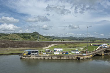 Panama Kanalı, Panama - 24 Temmuz 2023: Geniş manzara, SW rıhtımı Pedro Miguel Locks 'ta mavi bulutların altında traktörü çeken gemi.