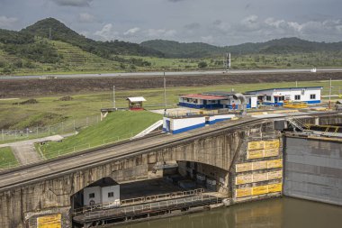 Panama Kanalı, Panama - 24 Temmuz 2023: Pedro Miguel Lock 'a güney ucunda binalarla giriş. Gri bulutların altındaki yeşil orman tepeleri