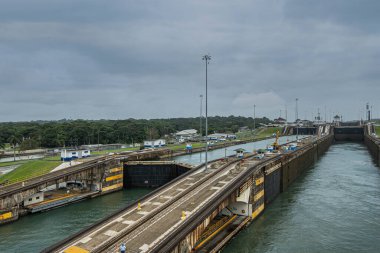 Panama Kanalı, Panama - 24 Temmuz 2023 Gatun 'dan Atlantik' e ulaşan su seviyeleri gri-mavi bulutlar altında kilitleniyor. Rıhtımlar ayrı ayrı iki su yolu. Yeşil kuşak ufukta