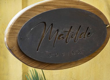 Cartagena, Kolombiya - 25 Temmuz 2023: 30. cadde boyunca, Matilde Cocina restoran tabelası sarı duvara yakın. Kahverengi tahtada siyah metal