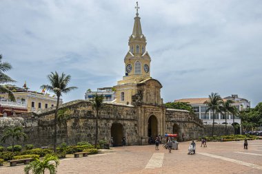 Cartagena, Colombia - July 25, 2023: Torre del Reloj and gate in remaining part of ramparts into old town center, square on  SE aisw under light blue cloudscape clipart