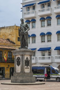 Cartagena, Colombia - July 25, 2023: Pedri de Heredia monument, bronze sculpture on stone pedestal on Plaza de los Coches. Police van in back in front of Writers Parliament building clipart