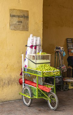 Cartagena, Colombia - July 25, 2023: Fresh lime juice pushcart closeup parked in passage of historic Administracion Roman building. Fresh fruit, iced juice and drinking cups clipart