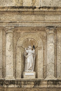 Cartagena, Colombia - July 25, 2023: Closeup, White statue of San Luis Beltran, Louis Bertrand, in brown-beige stone niche above entrance to Convento de Santa Domingo church. clipart