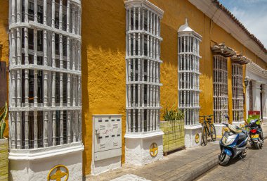 Cartagena, Kolombiya - 25 Temmuz 2023: Carrera 3, Carrera 3 boyunca pencerelerin önünde beyaz ahşap ızgara, Cuzco Cocina Peruana restoranına ait. Bir çift park etmiş scooter.