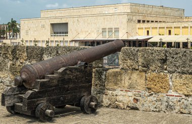 Cartagena, Kolombiya - 25 Temmuz 2023 Baluarte de San Ignacio surları ve altındaki kaleye top atışı. Mavi bulut manzarası. Arka taraftaki bej taşı kongre binası.