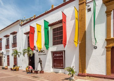 Cartagena, Kolombiya - 25 Temmuz 2023 Plaza del Parque o de Armas Meydanı. Modern sanat müzesi renkli bayraklı beyaz cephe. Küçük insan figürü heykel ve... insanlar mevcut