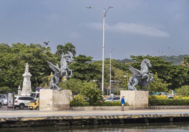 Cartagena, Kolombiya - 25 Temmuz 2023: Arkasında yeşil Centenario Parkı olan eski kasaba rıhtımının sonundaki Double Pegasus heykelleri. Beyaz mermer Nol Me Tanger, Dokunma Bana, anıt